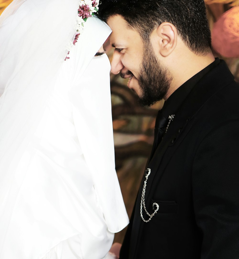 man in black suit kissing woman in white wedding dress