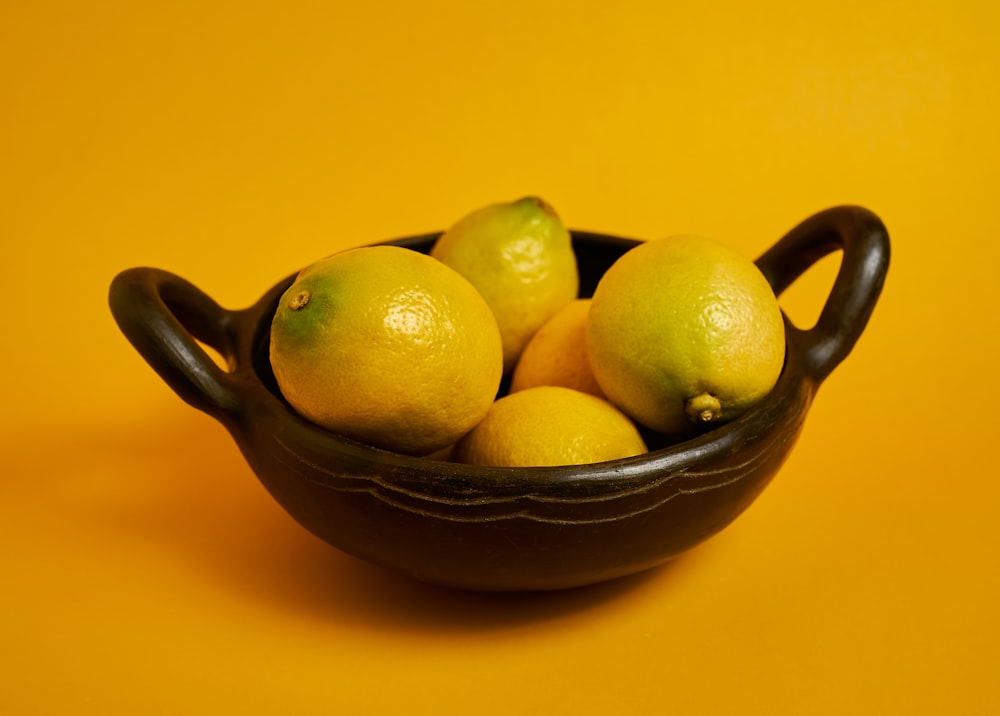 frutas cítricas amarelas na tigela de cerâmica preta