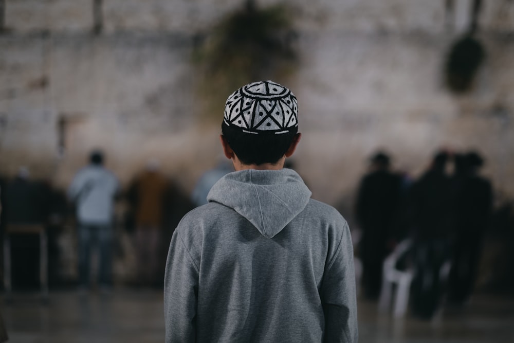 man in gray hoodie wearing black and white floral knit cap