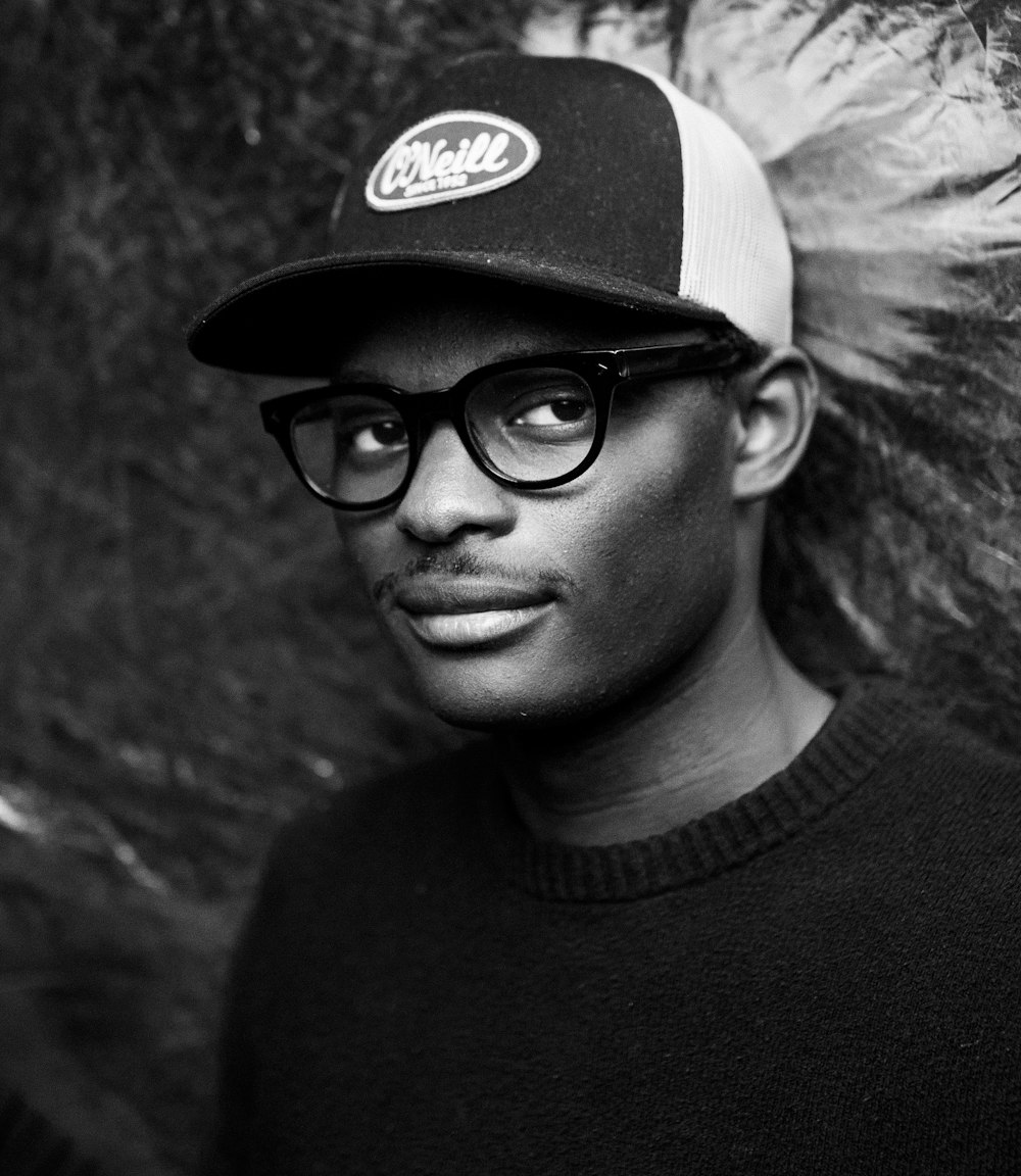 man in black crew neck shirt wearing black framed eyeglasses and black cap