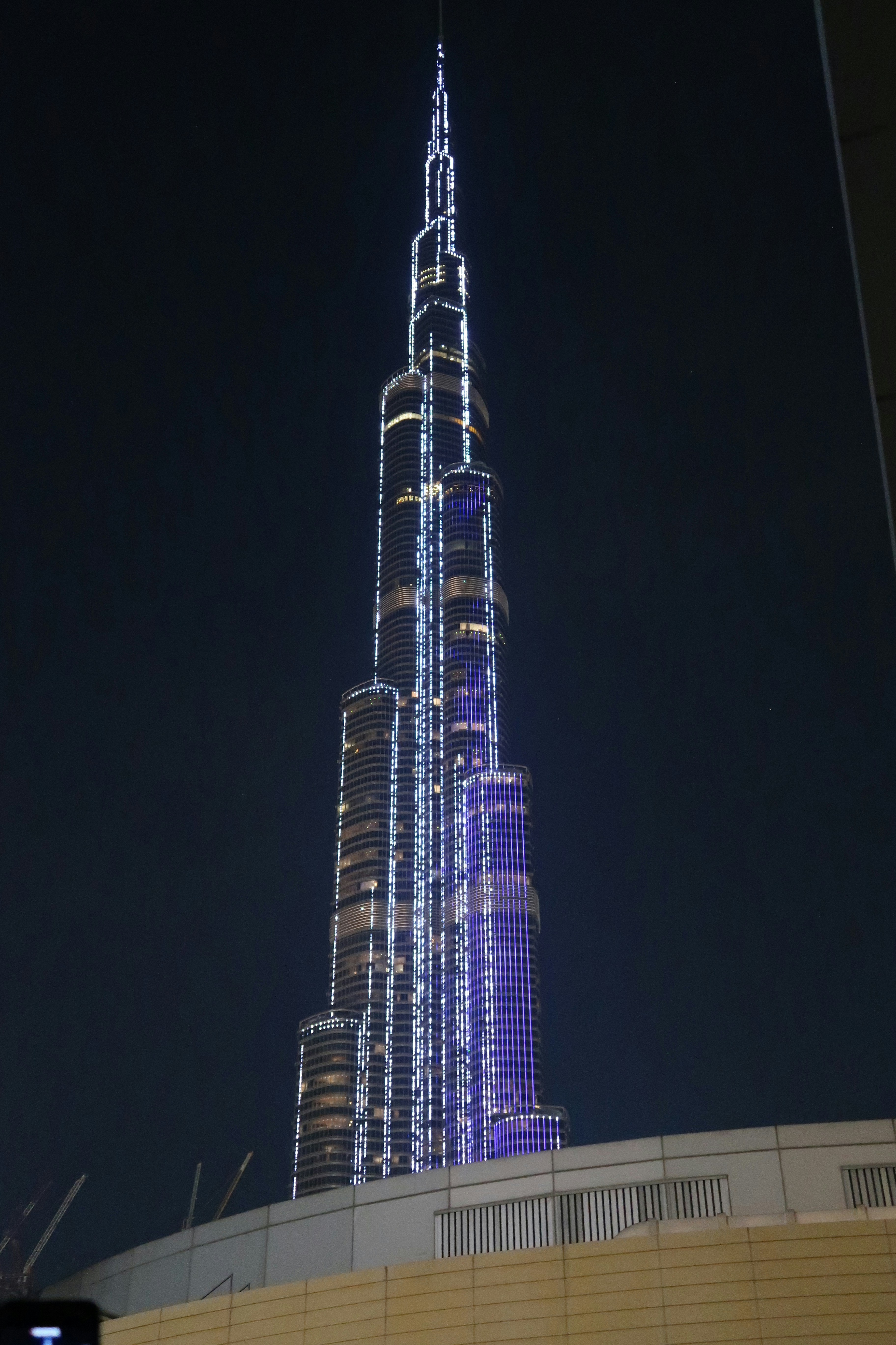 Dubai skyline at night with Burj Khalifa illuminated against a deep blue sky with city lights reflecting