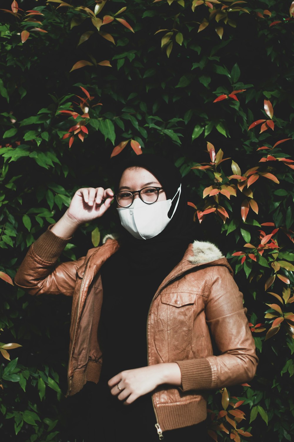 person in brown leather jacket holding white mask