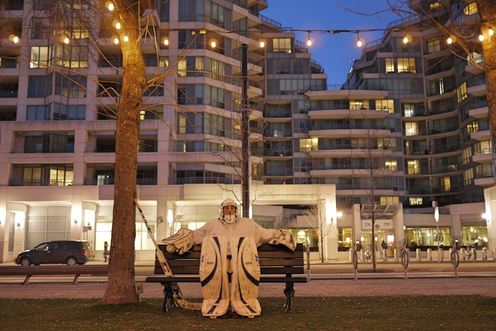 man sitting on bench statue near building during daytime