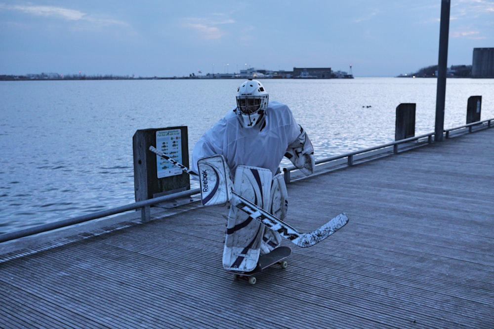 man in gray jacket and black pants holding black and white stick standing on dock during