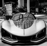 A sleek, futuristic sports car with a reflective surface displaying intricate roof patterns. The car's aerodynamic design features sharp angles and smooth curves, emphasizing its speed and sophistication. Positioned in an indoor setting with modern architecture in the background.