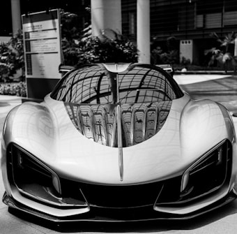 A sleek, futuristic sports car with a reflective surface displaying intricate roof patterns. The car's aerodynamic design features sharp angles and smooth curves, emphasizing its speed and sophistication. Positioned in an indoor setting with modern architecture in the background.