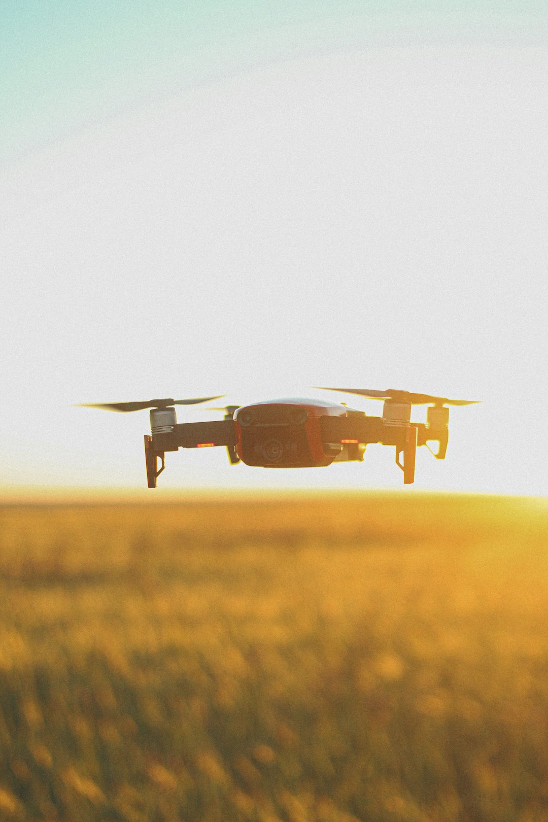 white and brown drone flying over brown grass field during daytime