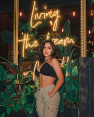 woman in black brassiere and white pants standing beside green plants