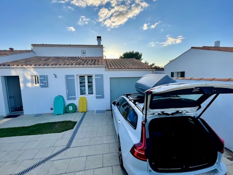 white and red car parked beside white and brown house
