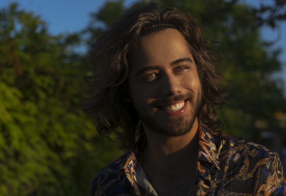 man in black and brown floral shirt smiling