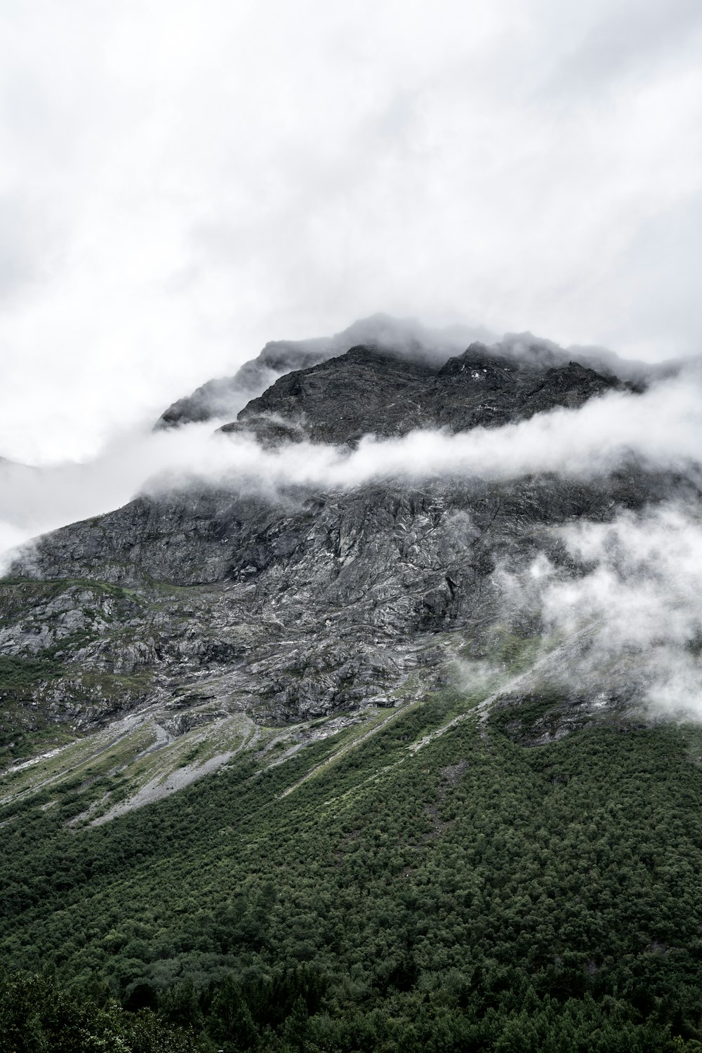 昼間の白い雲の下の緑と灰色の山