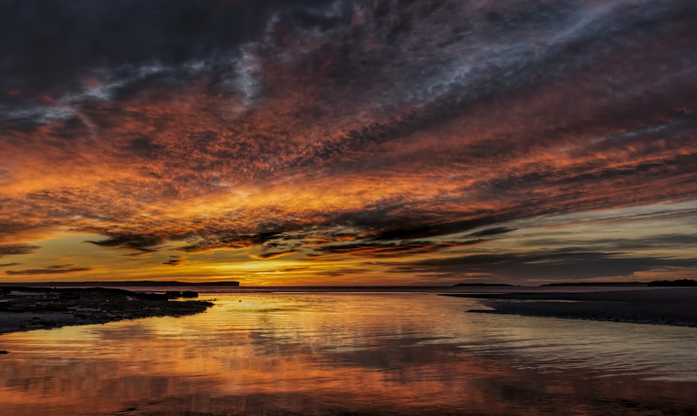 body of water under cloudy sky during sunset