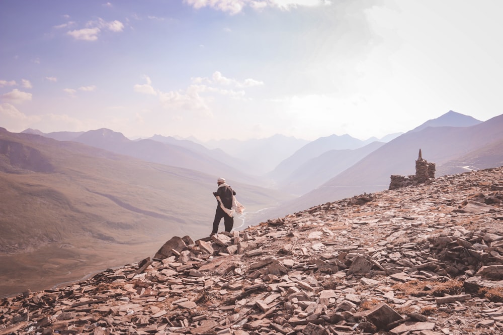 person in white shirt sitting on brown rock formation during daytime