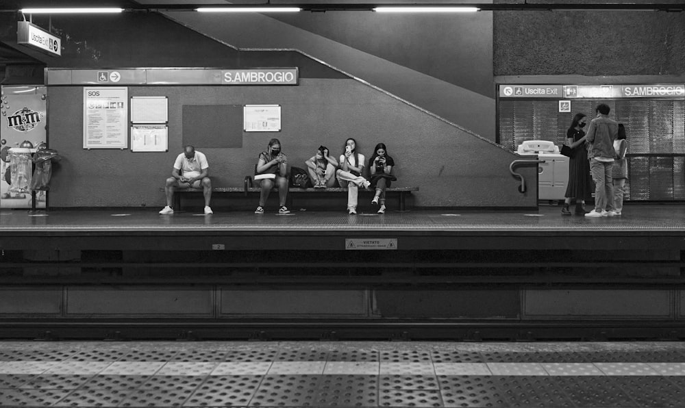 grayscale photo of people sitting on bench