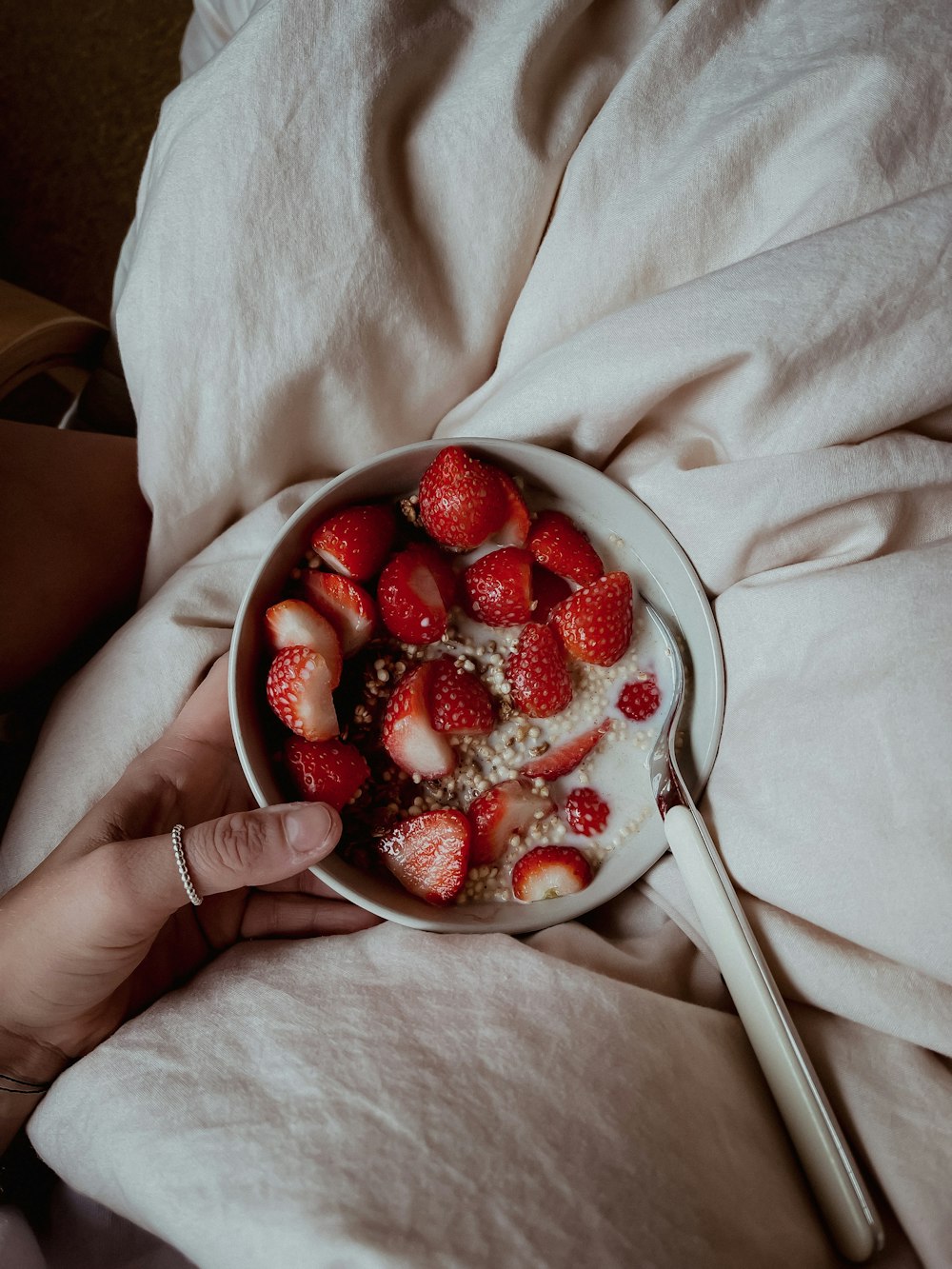person holding stainless steel spoon with strawberries