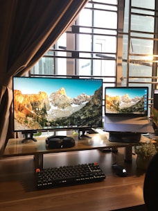 black flat screen computer monitor and black computer keyboard on brown wooden desk