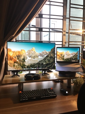 black flat screen computer monitor and black computer keyboard on brown wooden desk