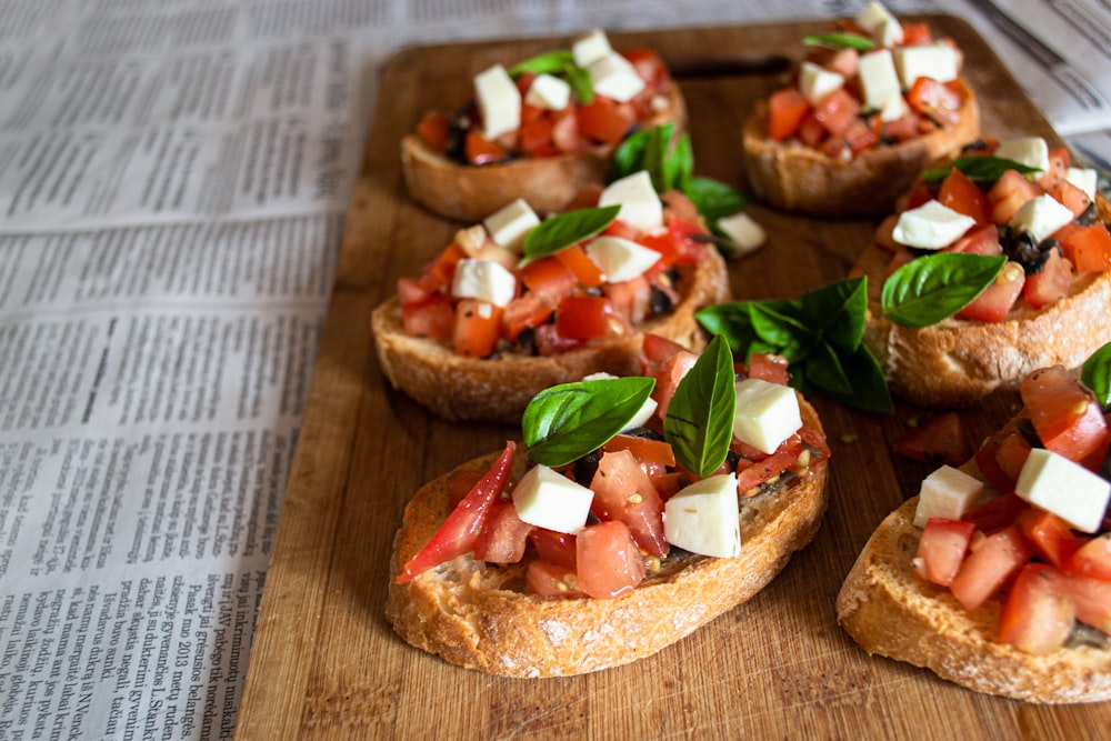 Pane a fette con pomodoro a fette e verdura a foglia verde su tagliere di legno marrone