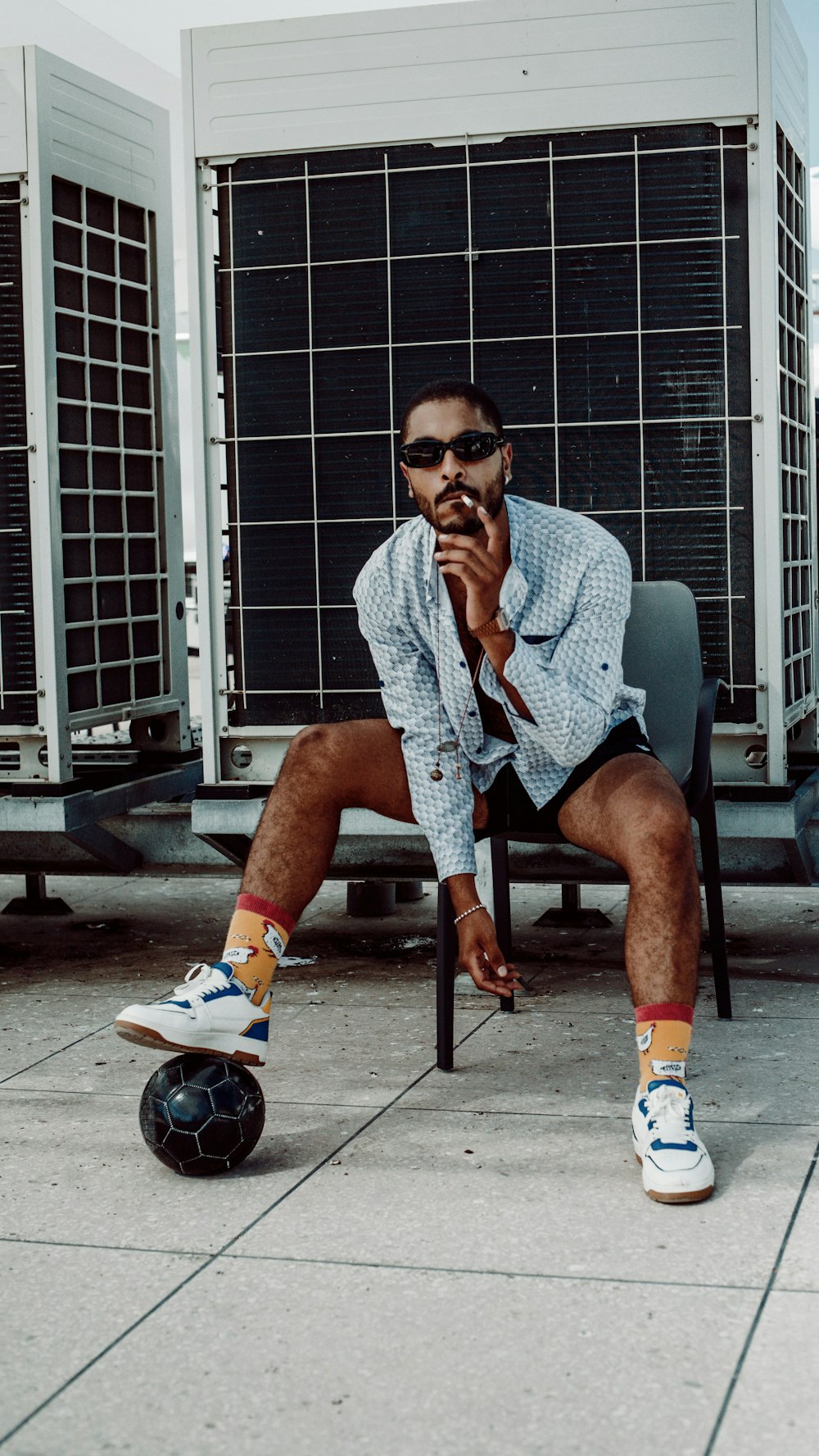 man in gray button up shirt and black shorts sitting on black chair