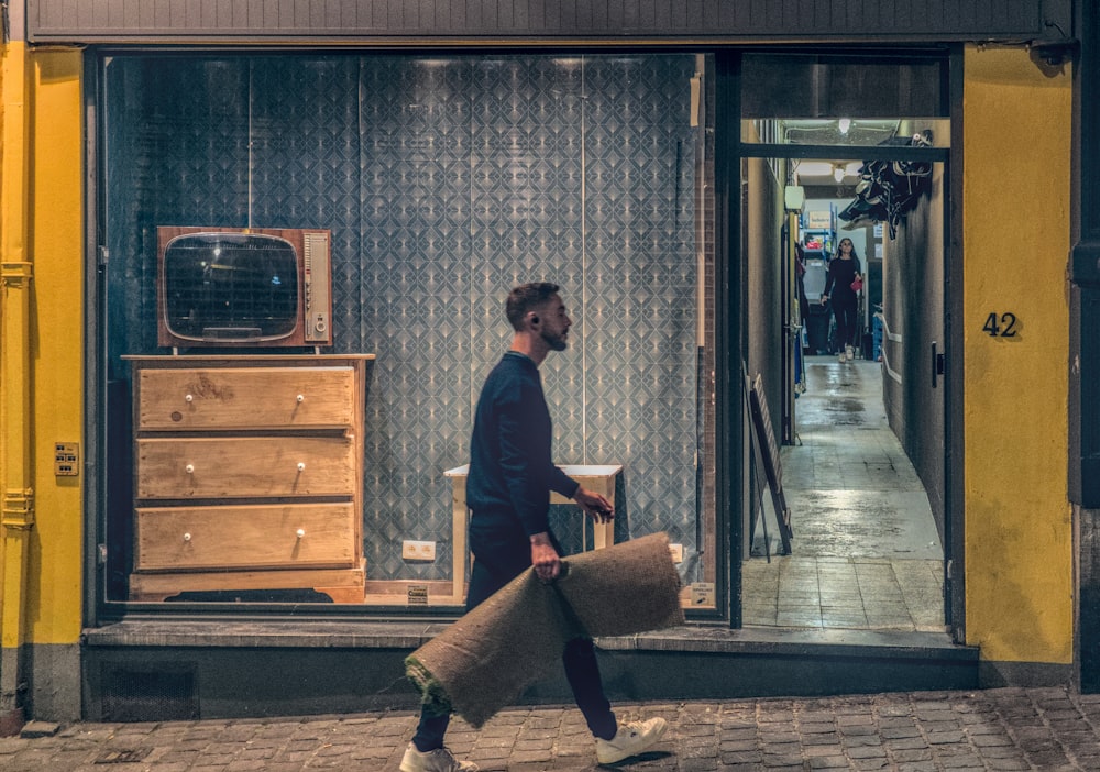 man in black long sleeve shirt and brown pants holding brown wooden board