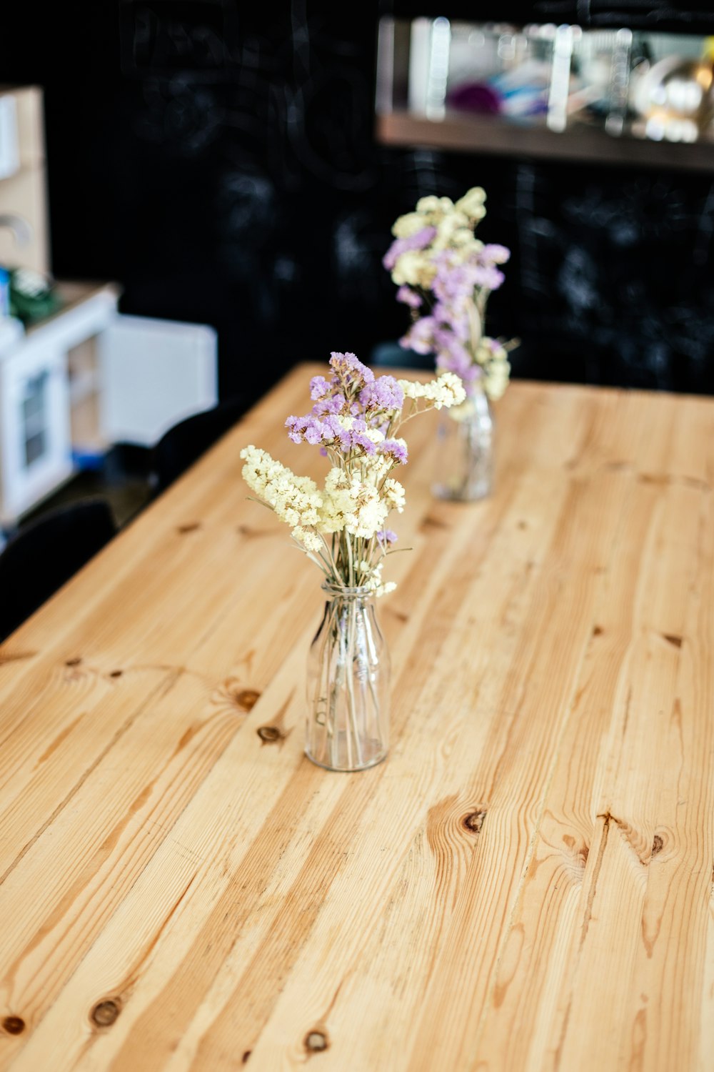 茶色の木のテーブルの上の透明なガラスの花瓶に白と紫の花