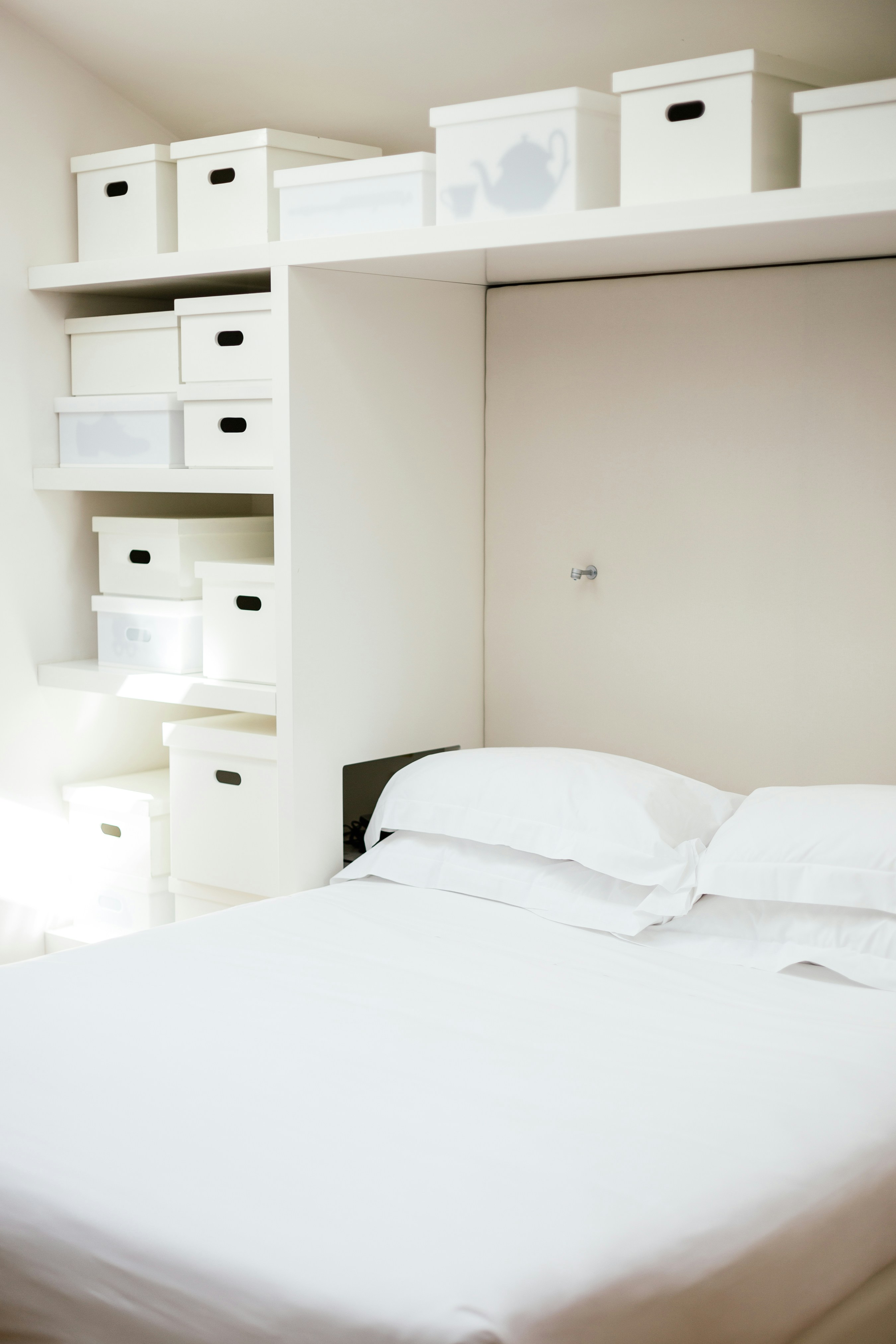 white bed linen near white wooden cabinet