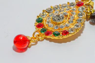 An ornate pendant featuring a stained glass-inspired design with deep crimson and emerald hues.