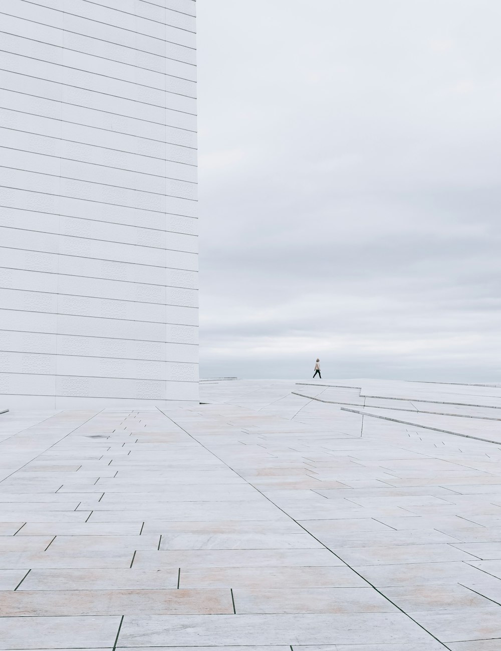 person in black jacket walking on white concrete building during daytime