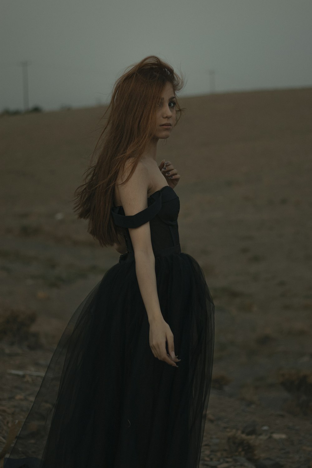 woman in black dress standing on brown field during daytime