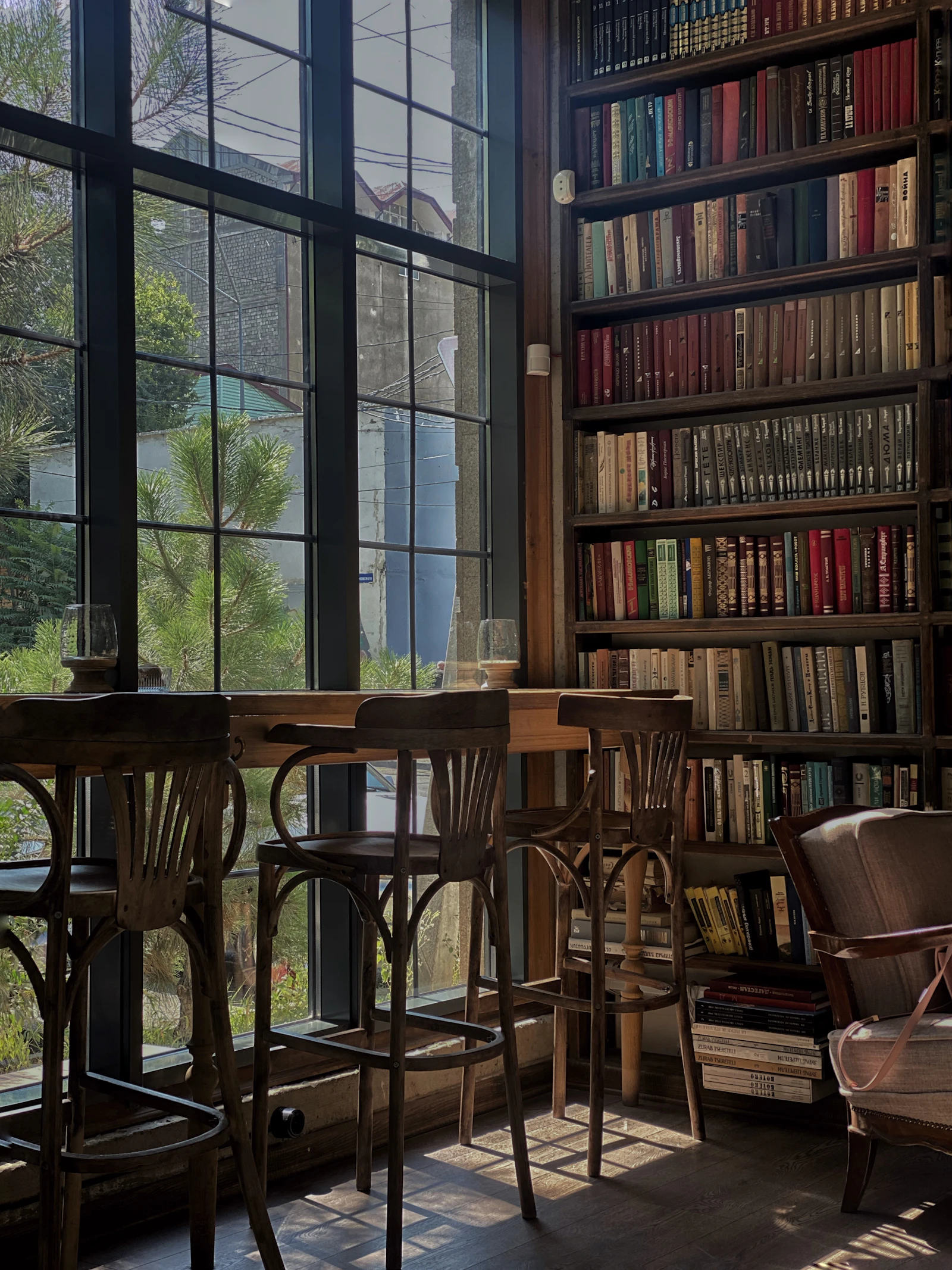 quiet library reading room with wooden tables by tall windows