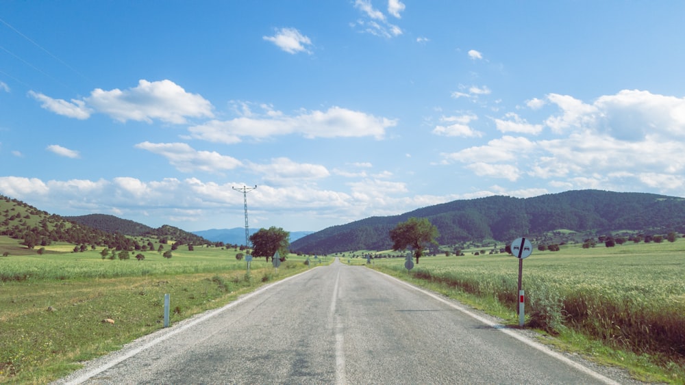 gray asphalt road near green grass field during daytime