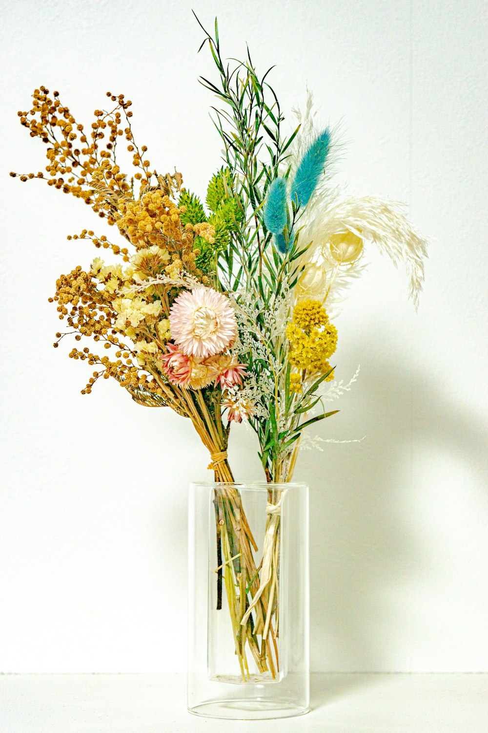 yellow and blue flowers in clear glass vase