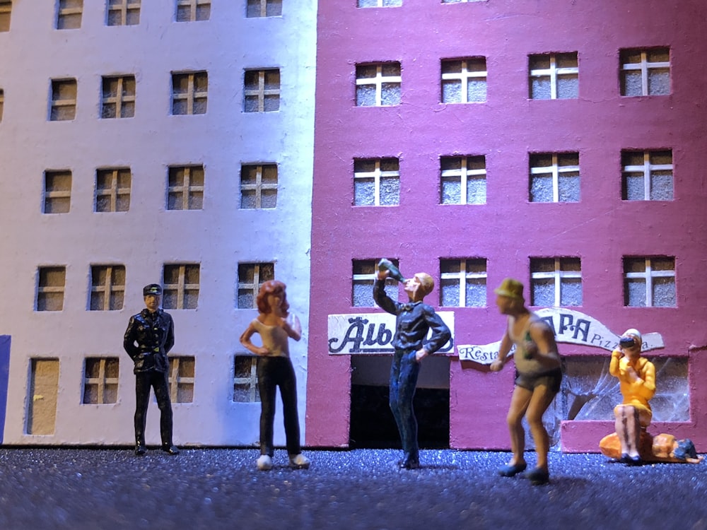 group of people standing in front of pink concrete building