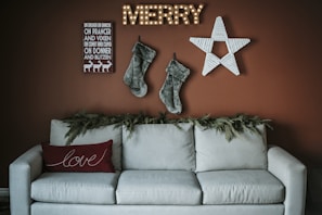 A warm living room scene showcasing Christmas pillows and wall art with heartwarming holiday messages.