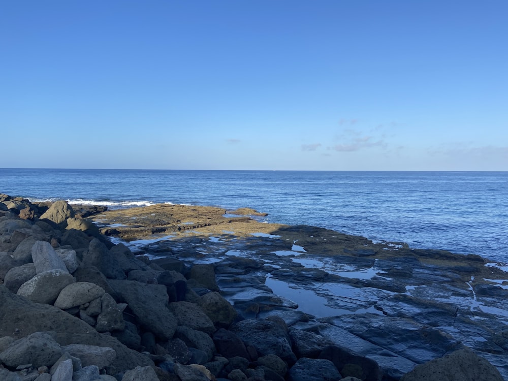 rocky shore with ocean waves crashing on shore during daytime