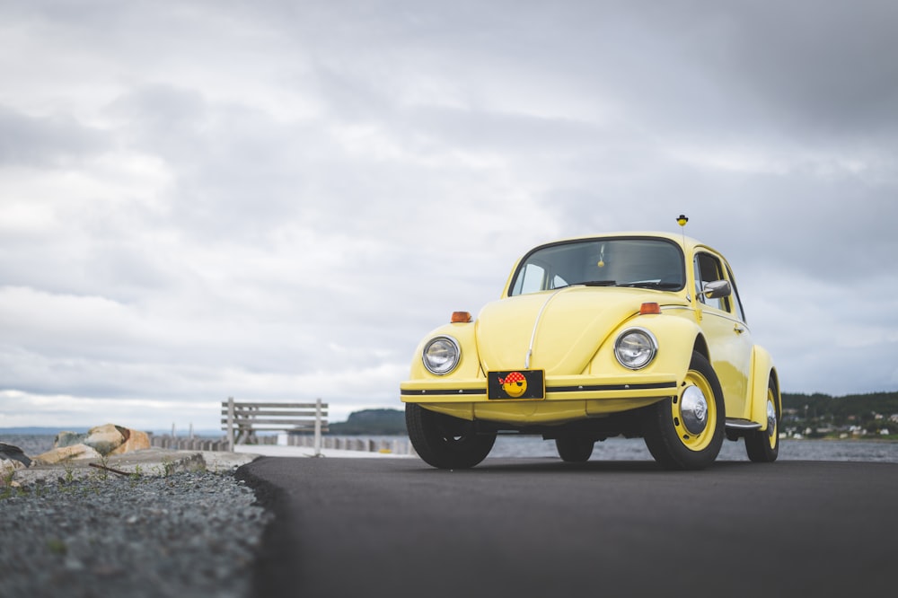 yellow volkswagen beetle on gray sand during daytime