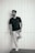 man in black crew neck t-shirt and white pants standing beside white wall