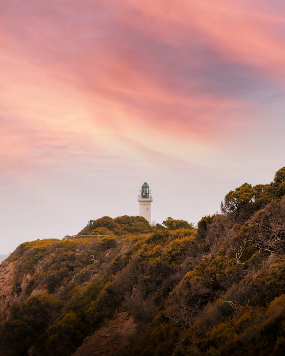 white lighthouse on top of hill during daytime