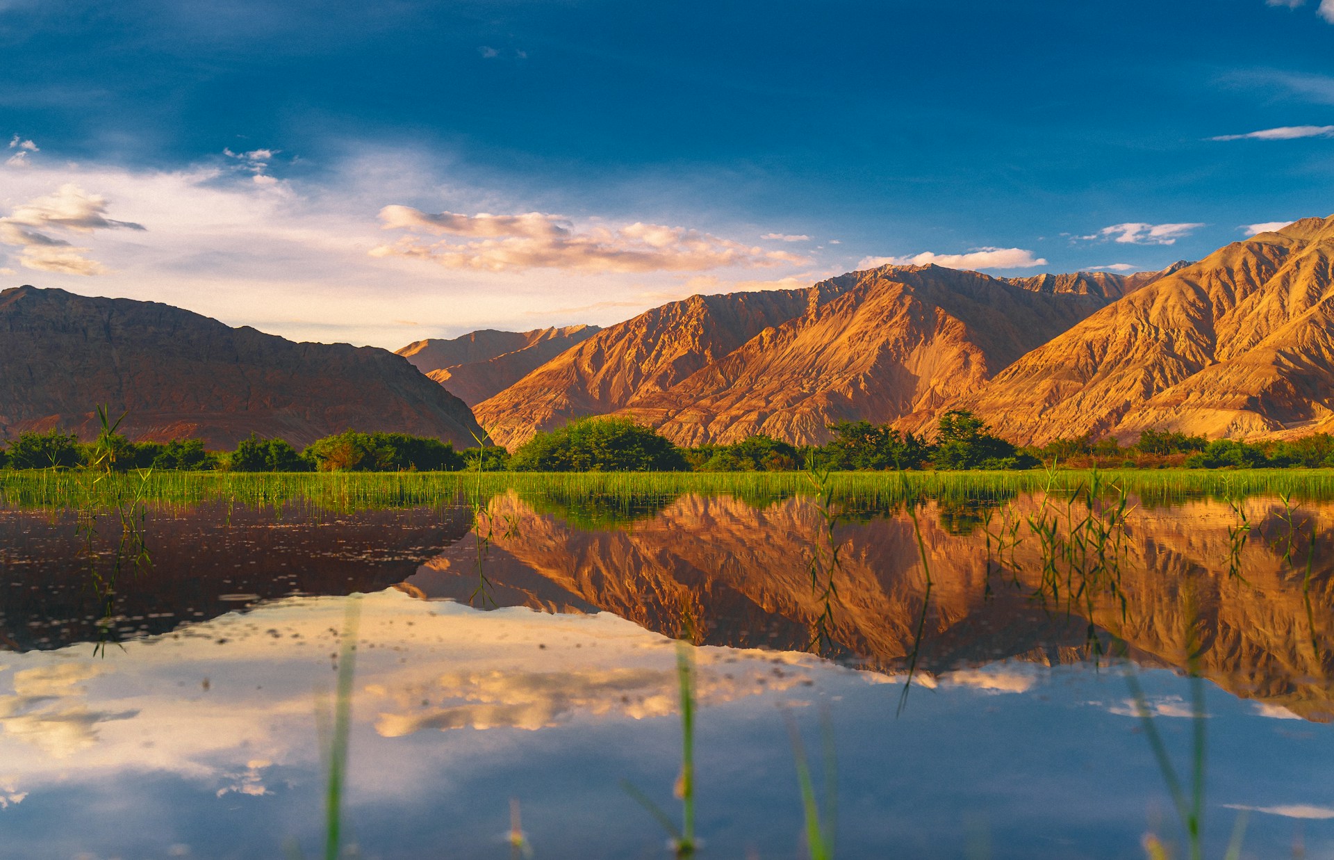 brown mountain beside lake under blue sky during daytime