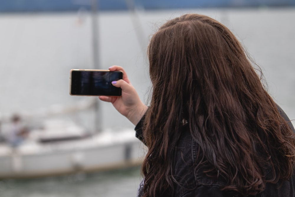 woman in black leather jacket holding black smartphone