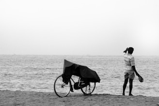 man in black and white long sleeve shirt and pants holding umbrella walking on beach