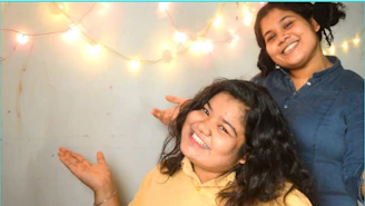 A wedding couple making silly faces inside the popup poses photo booth surrounded by colorful lights.