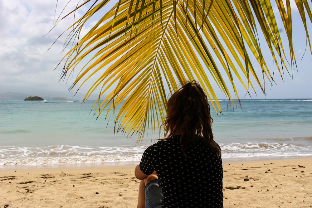 woman in black and white polka dot shirt standing on beach during daytime