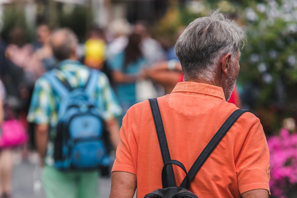 man in orange t-shirt with black backpack