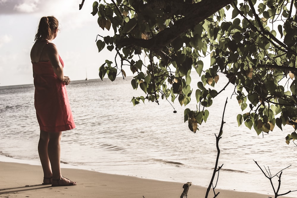 woman in red dress standing on beach during daytime
