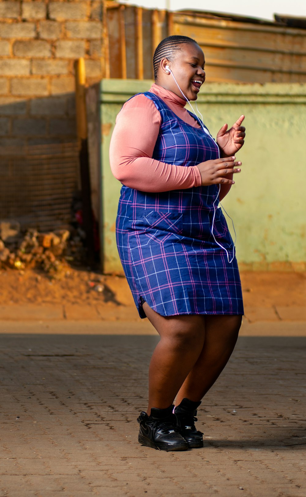 woman in blue and white plaid sleeveless dress standing on brown sand during daytime