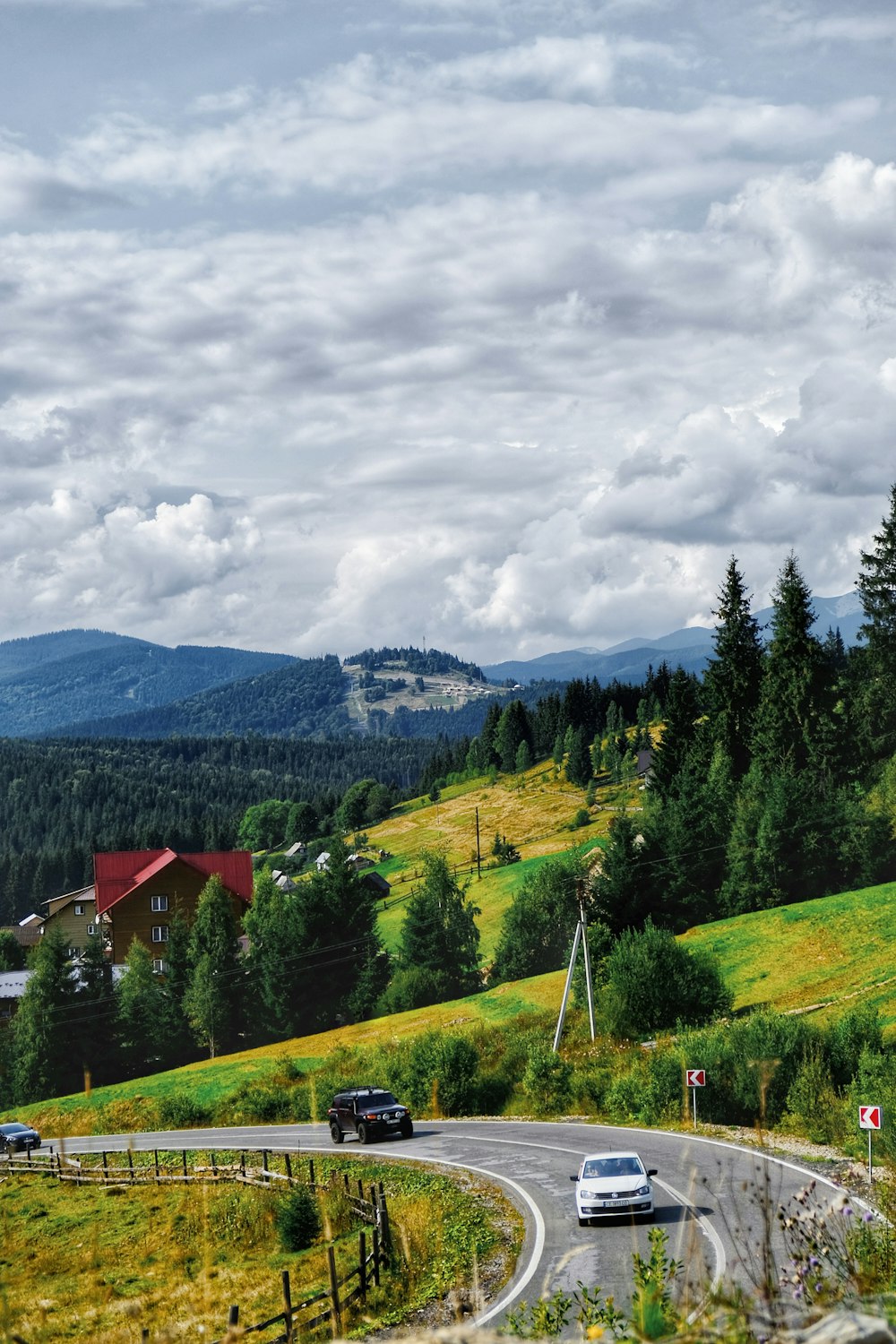 red house on green grass field near green trees under white clouds during daytime