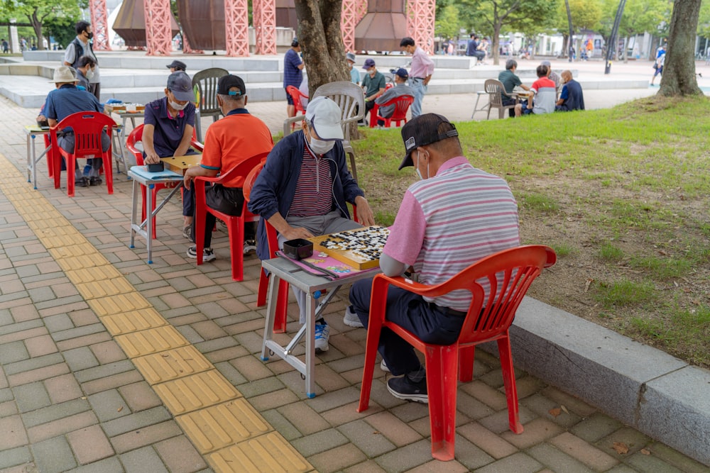 people sitting on red plastic chairs during daytime
