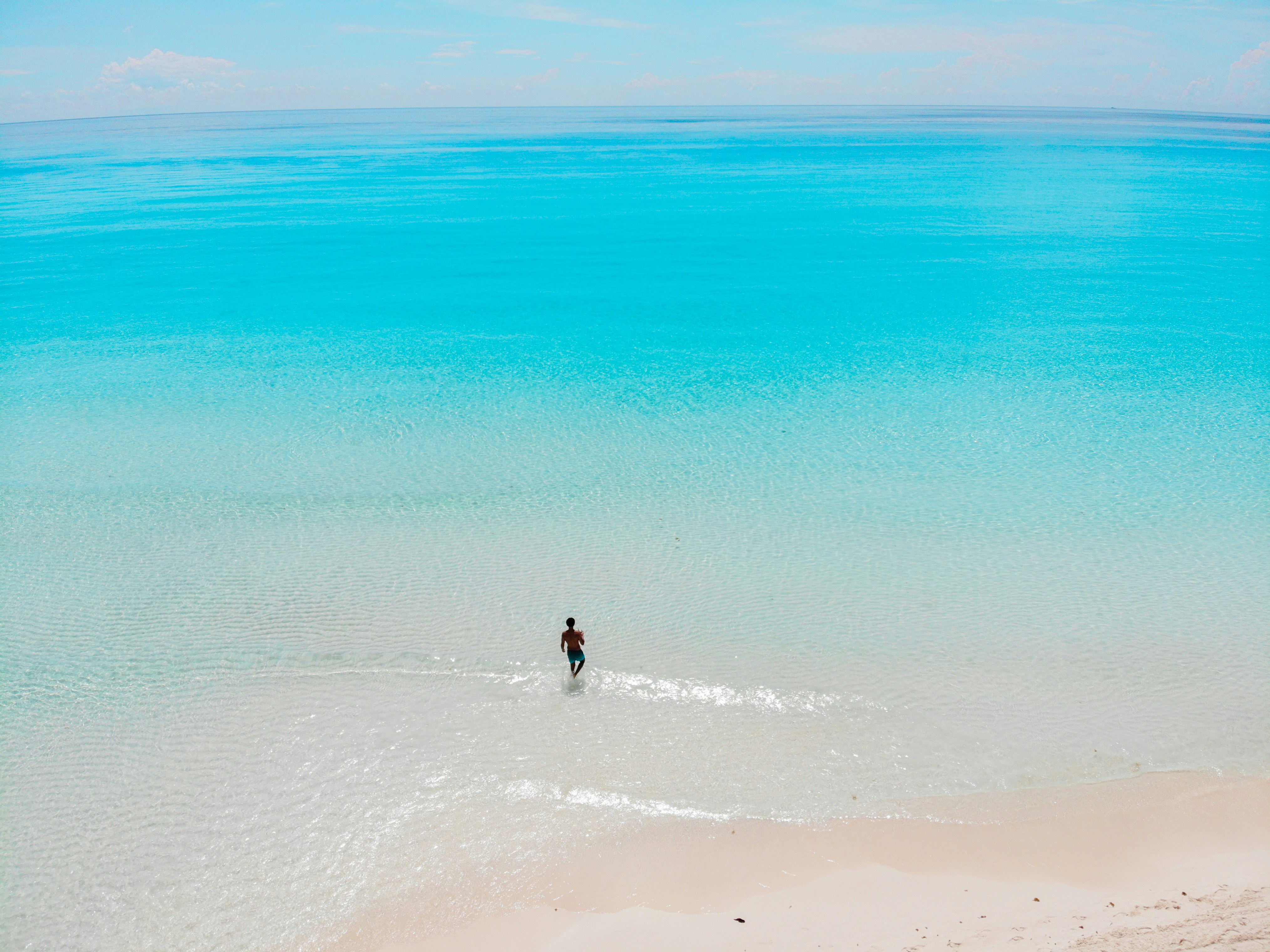 person in black shirt walking on beach during daytime