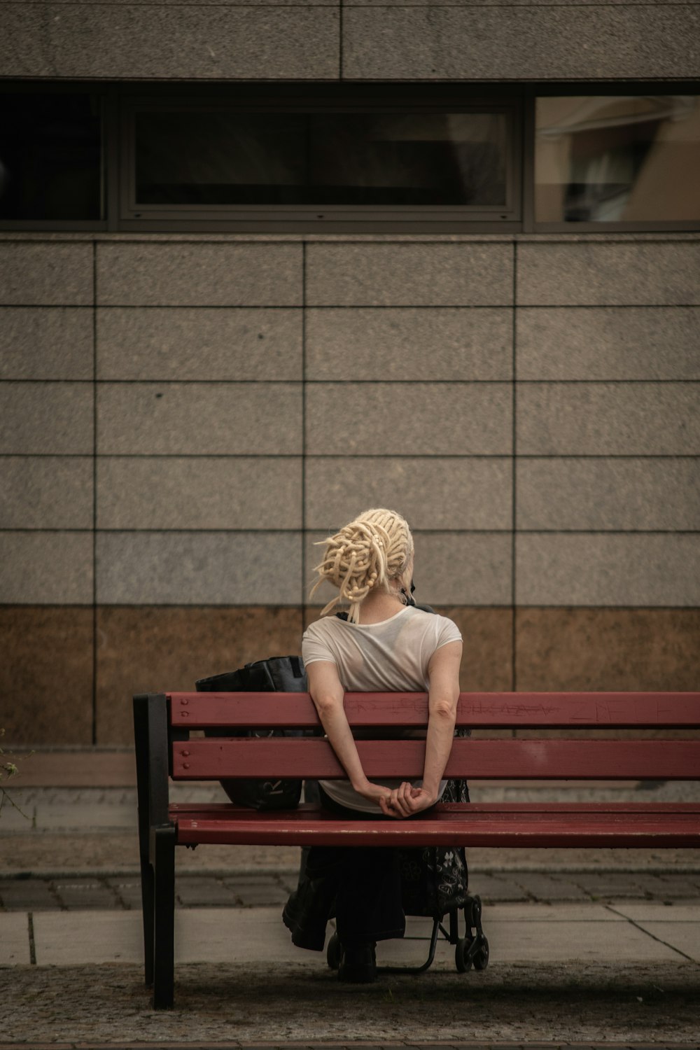 femme en débardeur gris assise sur un banc en bois marron